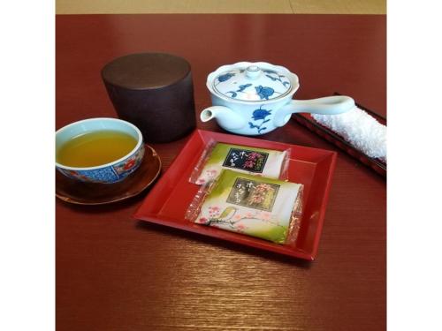 Oshuku Onsen Hotel Uguisu - Vacation STAY 27315v في Shizukuishi: طاولة مع كوب من الشاي وصينية حمراء