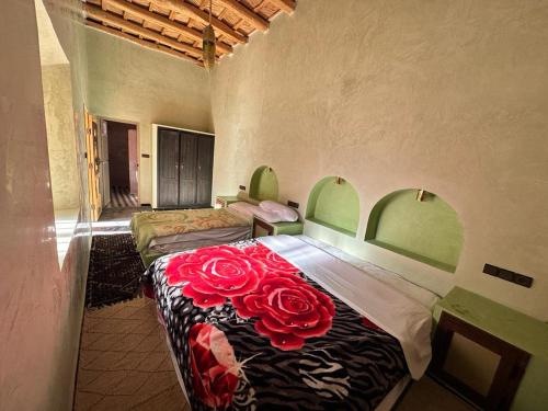 a bedroom with a bed with red roses on it at Gîte d'étape Tamaloute in Bou Drarar