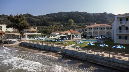 un complejo con sombrillas azules y blancas y agua en Maria Mare Apart-hotel, en Argassi