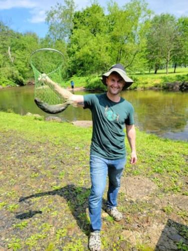 a man holding a net in front of a river at Boat House in Downingtown