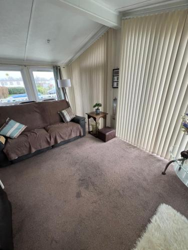 a living room with a couch and some windows at 40A Oak Village- 2 Bedroom Lodge on Grange Leisure Park in Mablethorpe