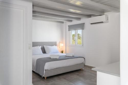 a white bedroom with a bed and a window at ELEVEN KEYS APARTMENTS in Vrisi/ Mykonos