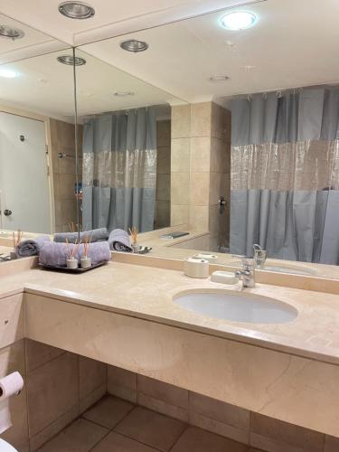 a bathroom with a sink and a large mirror at אלמוג על הים in Haifa