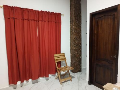 a wooden chair sitting in front of a red curtain at Casa Palmamar in Olón