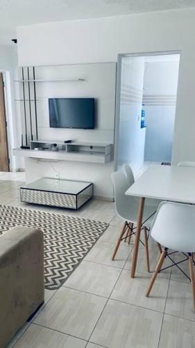 ein Wohnzimmer mit einem TV, einem Tisch und Stühlen in der Unterkunft Apartamento mobiliado em Aracaju in Aracaju