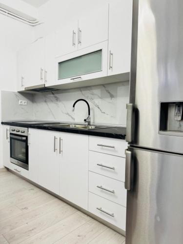 a kitchen with white cabinets and a stainless steel refrigerator at Thomais Guesthouse in Kavala