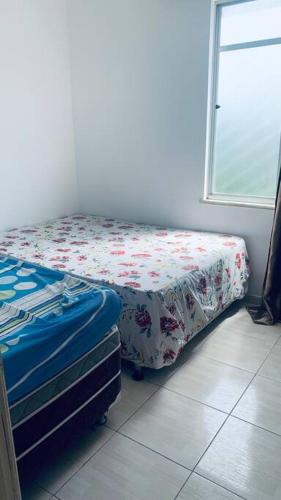 ein Schlafzimmer mit einem Bett mit einem geblümten Laken in der Unterkunft Apartamento mobiliado em Aracaju in Aracaju