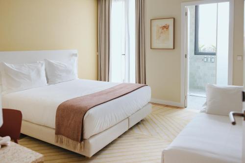 a bedroom with a large white bed and a window at NINE DOTS Azorean Art Boutique Hotel in Ponta Delgada