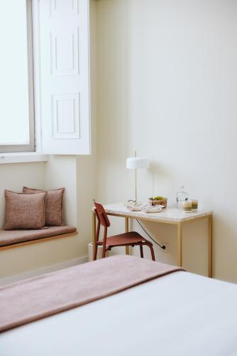 a bedroom with a bed and a desk with a chair at NINE DOTS Azorean Art Boutique Hotel in Ponta Delgada