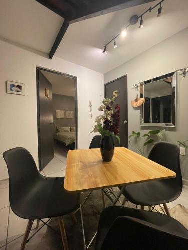 a dining room table with chairs and a vase with flowers at Exclusivas Habitaciones al Oriente in Mexico City