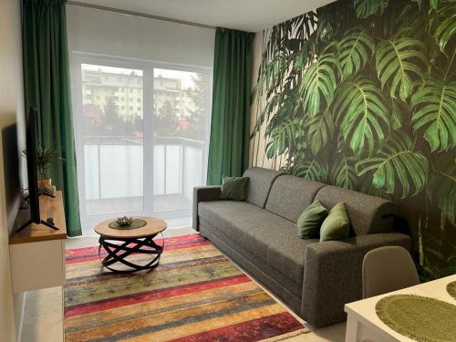 ein Wohnzimmer mit einem Sofa und grünen Vorhängen in der Unterkunft Apartament Zacisze 13 in Piaseczno