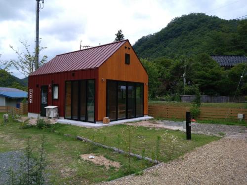 um celeiro vermelho com janelas de vidro num quintal em Ayu no Sato Park Campsite - Vacation STAY 42240v em Shōbara