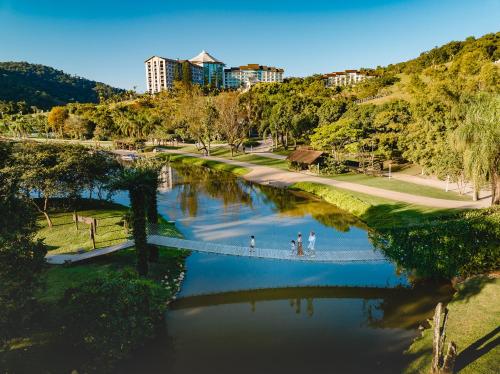 dos personas caminando a través de un puente sobre un río en Fazzenda Park Resort en Gaspar