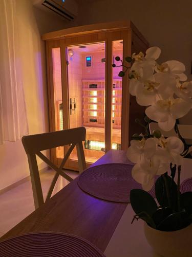 Cette chambre comprend une table et un vase avec des fleurs blanches. dans l'établissement Eternity Apartmanház, à Keszthely