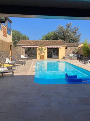 une grande piscine bleue devant une maison dans l'établissement Les clés du Sud Bormes 35m2, à Bormes-les-Mimosas