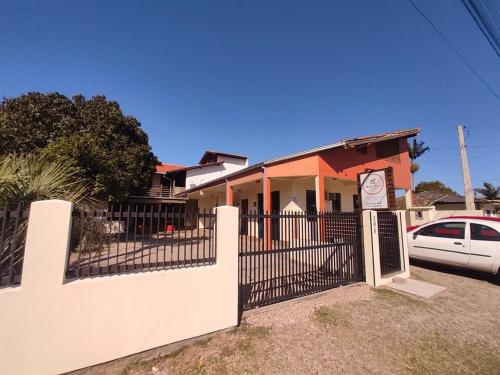 uma casa com uma vedação e um cartaz à frente dela em Pousada Areia Nova em Garopaba