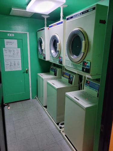 een wasruimte met wasmachines en drogers en een groene muur bij HOTEL SEAGULL - Vacation STAY 36269v in Izumi-Sano