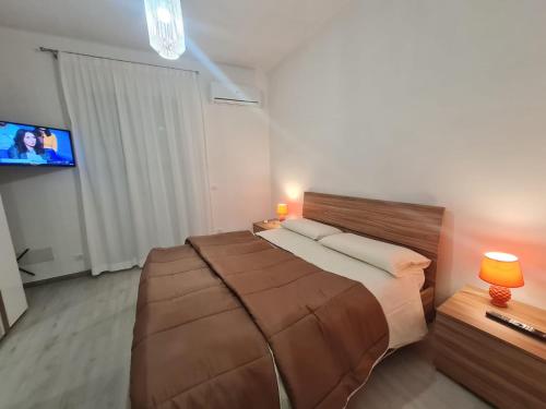 een slaapkamer met een groot bed en een flatscreen-tv bij Casetta Bella Nonna Rosetta in Mondello
