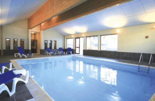 a large swimming pool with blue chairs in a building at Chalets Du Galibier I - Studio pour 4 Personnes 654 in Valloire