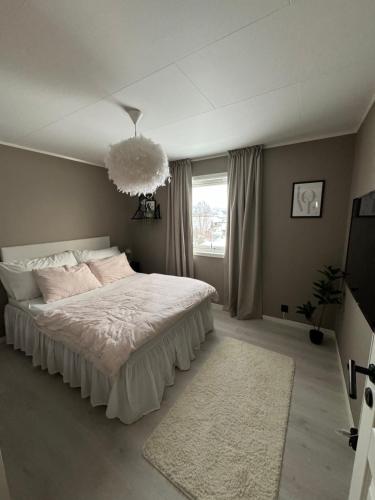 a bedroom with a white bed and a chandelier at Hus med 2 soverom in Sortland