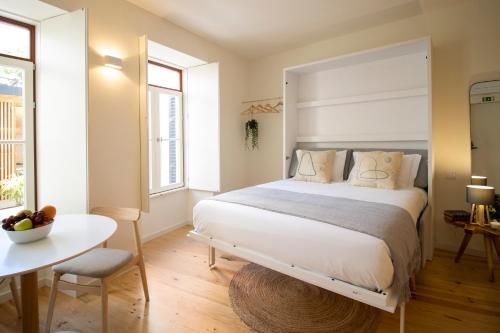 Un dormitorio con una gran cama blanca y una mesa en Casa da Encomenda @ Casas do Pátio (6), en Coímbra