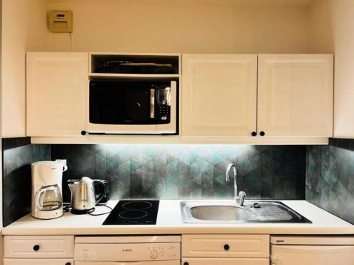 une cuisine avec un évier et un micro-ondes dans l'établissement Chalet De L'arvette - 2 pièces cabine 4 personnes exposé Nord-Ouest MAE-3694, à Valloire