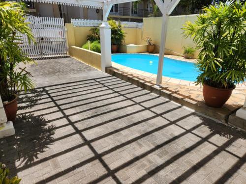 a swimming pool in a yard with trees and a fence at Bungalow Forgetti at Trou aux Biches with private swimming pool in Trou aux Biches