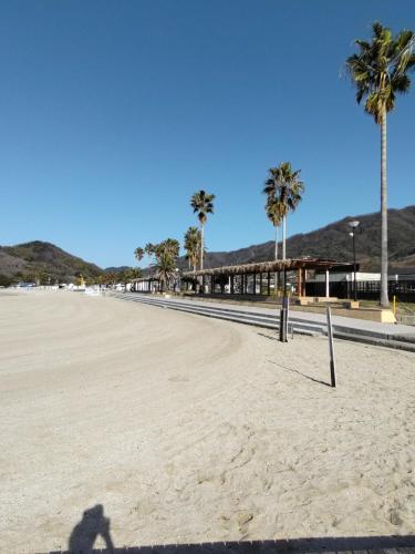 una sombra de una persona parada en una playa con palmeras en Shimanami Osayo no Yado - Vacation STAY 16166 en Onomichi