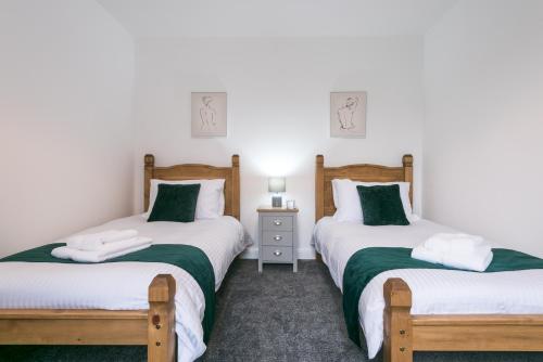 a bedroom with two beds with green and white sheets at Rio's Retreat in Cottingham