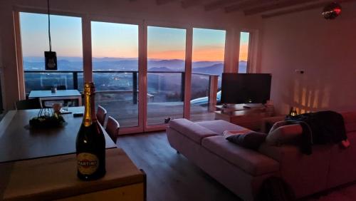 a living room with a couch and a bottle of wine at Koča z razgledom in Križe