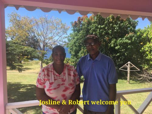 Ein Mann und eine Frau stehen neben einem Zaun in der Unterkunft The Pink House in Choiseul