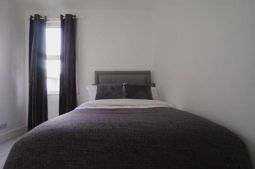 a bed in a white room with a window at Milton Place in London