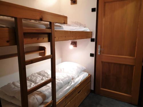 Zimmer mit 3 Etagenbetten und einer Tür in der Unterkunft Residence La Corniche - Studio pour 4 Personnes 154 in Morzine
