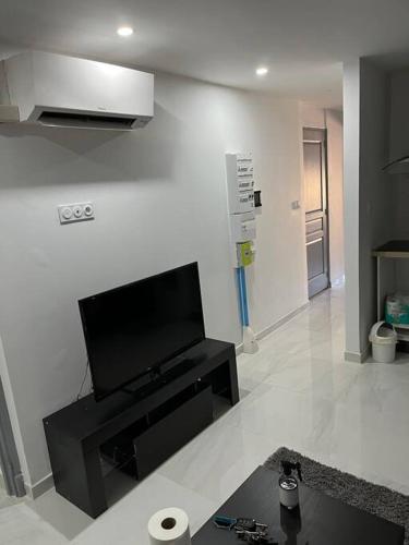 un salon avec une télévision à écran plat sur un mur dans l'établissement T2 dans une villa, à Bagnols-sur-Cèze