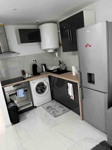 a kitchen with a refrigerator and a washing machine at T1 dans une villa in Bagnols-sur-Cèze