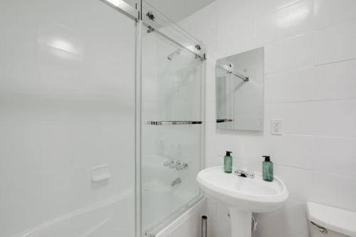 een witte badkamer met een wastafel en een douche bij Bay Ridge Haven: Contemporary Charm in Brooklyn in Brooklyn