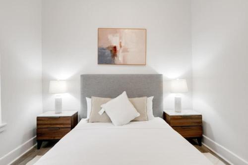 een slaapkamer met een wit bed met 2 nachtkastjes en 2 lampen bij Bay Ridge Haven: Contemporary Charm in Brooklyn in Brooklyn