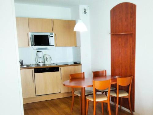 une petite cuisine avec une table et des chaises en bois dans l'établissement Résidence Pic Du Midi - Apt n°145 - 1er étage - Bâtiment Hourquette MAE-8754, à La Mongie