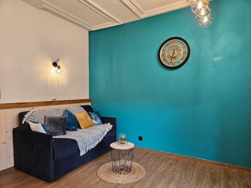 a living room with a couch and a blue wall at Gîte Bleuet, petit LOFT 2 à 6 personnes, avec salle de jeux et SPA dans la résidence in Ventron