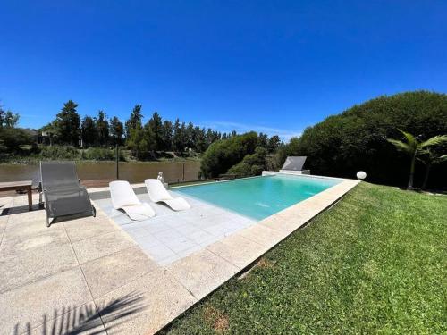 a swimming pool with two chairs and a table at Casa minimalista con piscina y muelle en Nordelta-Villanueva in Belén de Escobar