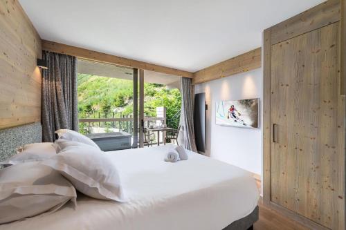 a bedroom with a large white bed and a window at Résidence Phoenix - 4 Pièces pour 8 Personnes 084 in Courchevel