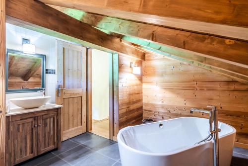 La salle de bains est pourvue de murs en bois, d'une baignoire et d'un lavabo. dans l'établissement Chalet La Passionata - Chalets pour 8 Personnes 154, à Morzine