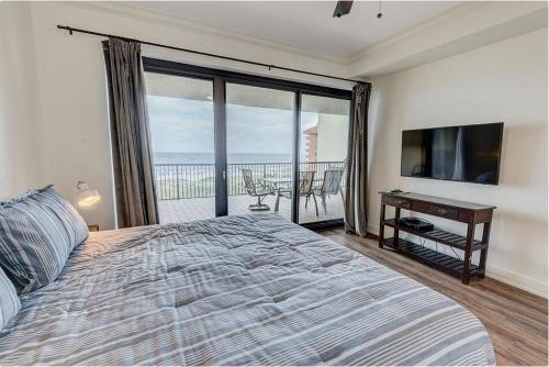 een slaapkamer met een bed, een televisie en een balkon bij Grand Pointe Unit 613 in Orange Beach