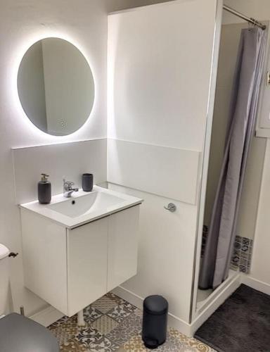 une salle de bain blanche avec un lavabo et un miroir dans l'établissement Jolie maison mesquéraise avec jardin proche mer, à Mesquer