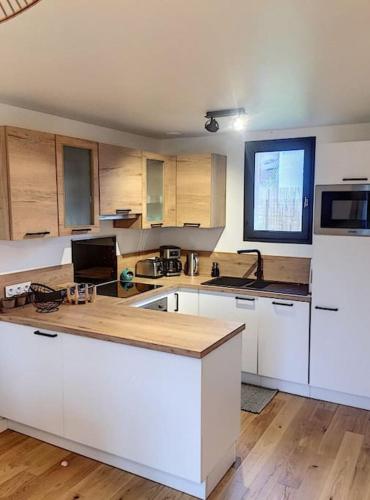 une cuisine avec des armoires blanches et un comptoir dans l'établissement Jolie maison mesquéraise avec jardin proche mer, à Mesquer