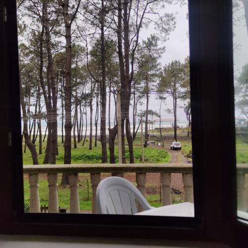 a window with a white chair looking out at a park at 4 Bed Villa-Sleeps 8-Parking-Garden-Sea View in Ureki