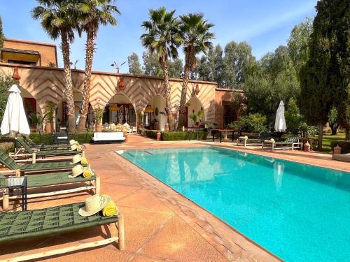 einen Pool mit Chaiselongue neben einem Haus in der Unterkunft Palais Dobra in Marrakesch