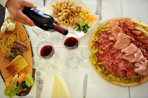 a person is pouring wine into a plate of food at Biker Hotel Al Gallo Forcello in Passo Pramollo