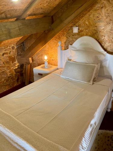 a bedroom with a white bed with a stone wall at Casa do Avô Grande in Esposende