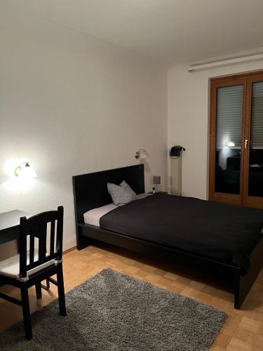 a bedroom with a black bed and a chair at Privatzimmer in zentraler Lage in Geislingen (Steige) in Geislingen an der Steige